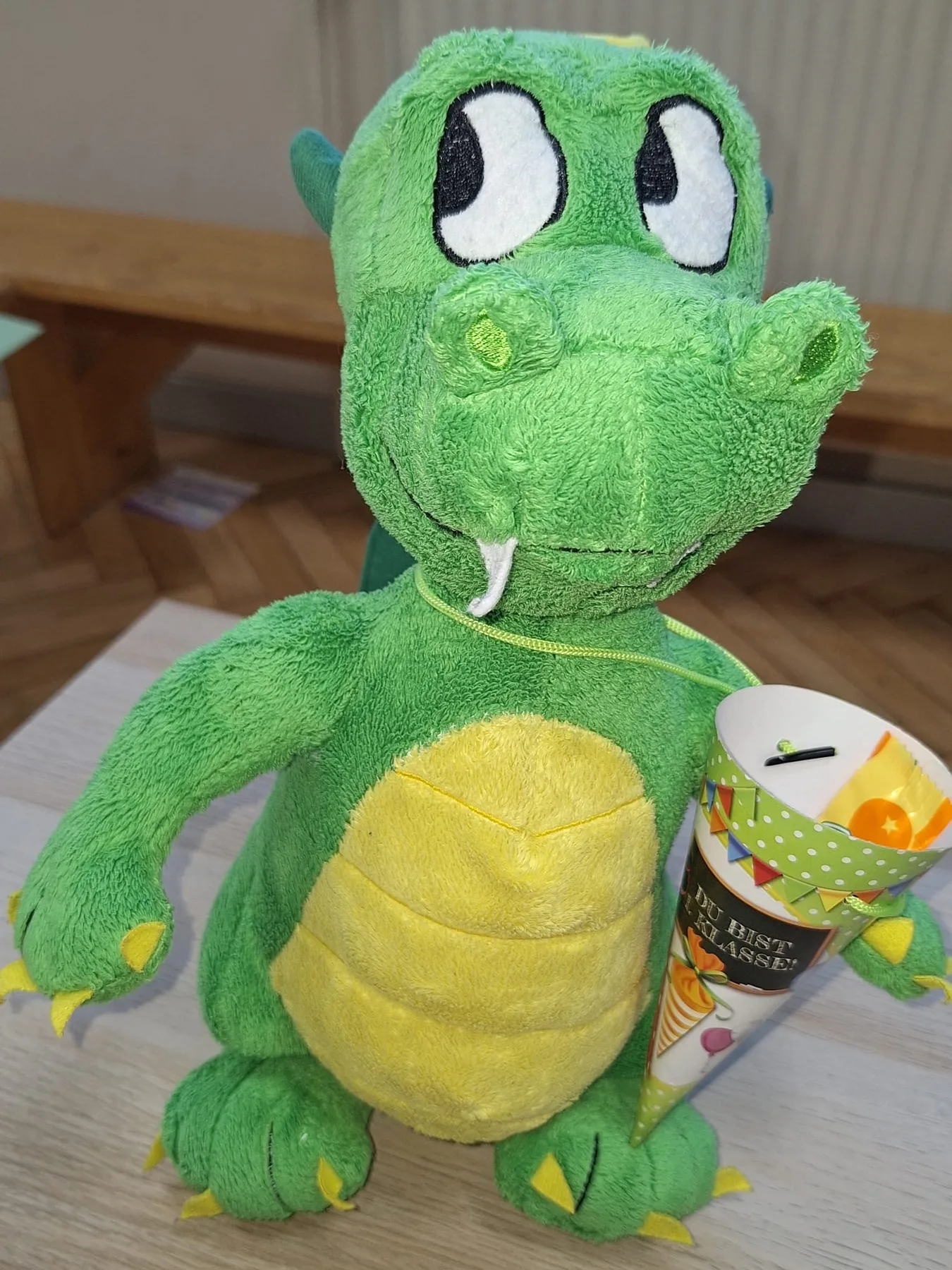 Ein grüner Schuldrache mit Schultüte.